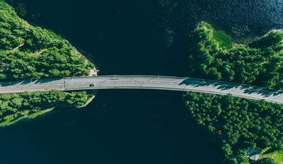 Bridge over water with surrounding greenery, aerial view