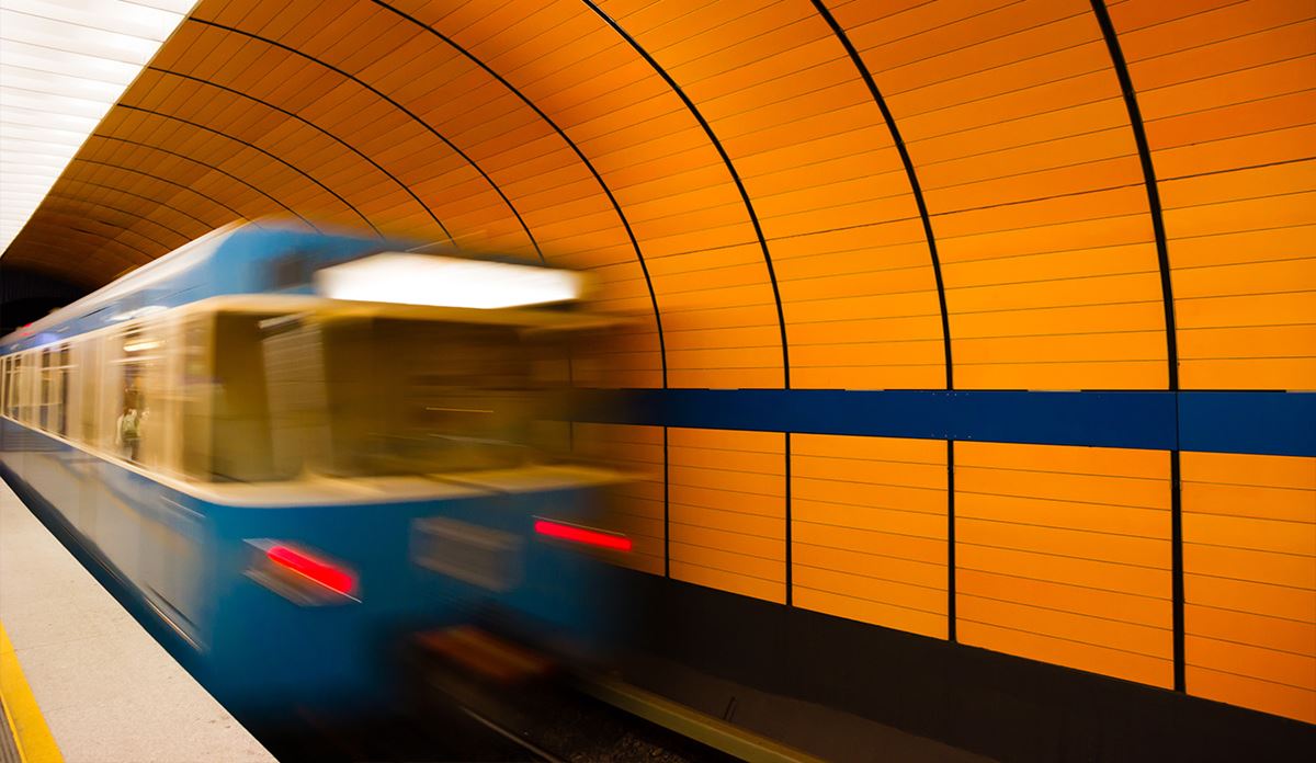 Blue subway train speeding through an orange tiled station tunnel