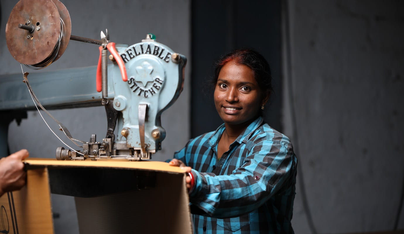 An Indian woman stands next to machinery