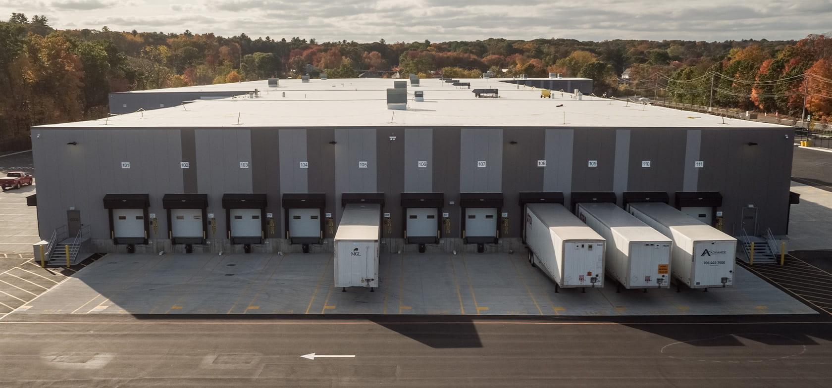 A large warehouse distribution center with multiple loading docks, with some trucks backed into them.