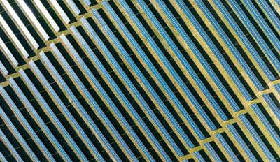 Aerial view of neatly arranged rows of solar panels installed on open land
